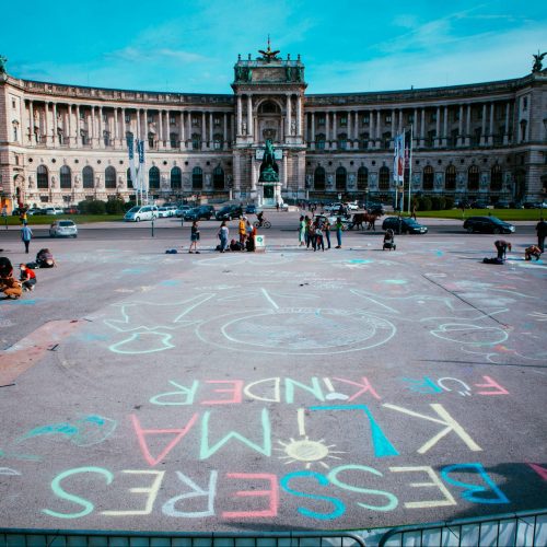 Foto vom Heldenplatz auf die Hofburg in Wien. Am Boden sind Botschaften zum Klimaschutz mit bunter Kreide aufgemalt.